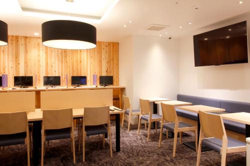 松本松本M酒店 的一间带桌椅和电视的用餐室