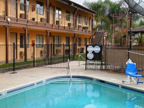 贝克斯菲尔德最佳经济套房汽车旅馆的一个带蓝色椅子的游泳池和一座建筑