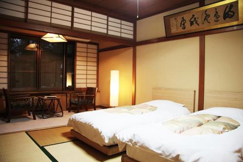 富士河口湖河口湖酒店的一间带两张床和一张桌子的卧室以及一间用餐室