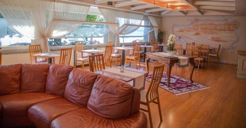 韦尔巴尼亚阿卡多斯酒店的餐厅配有皮沙发、桌椅