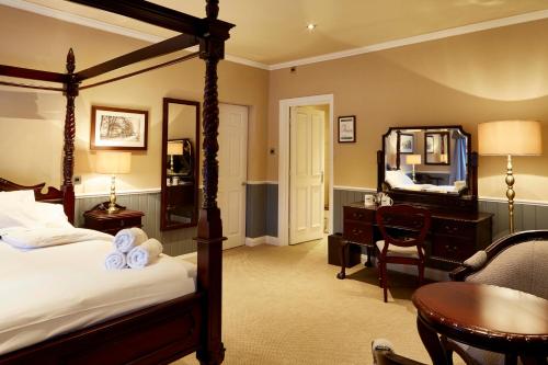 克努斯福德The Golden Pheasant的一间卧室配有一张床、一张书桌和一面镜子