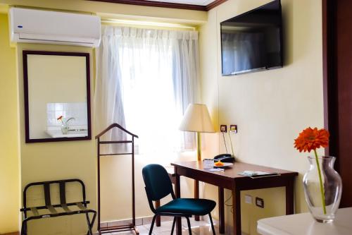 圣萨尔瓦多Hotel Gardenia Inn的客房设有书桌、椅子和窗户。