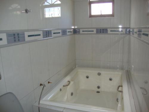 特林达迪Pousada Jesus De Nazare的白色瓷砖浴室内的白色浴缸