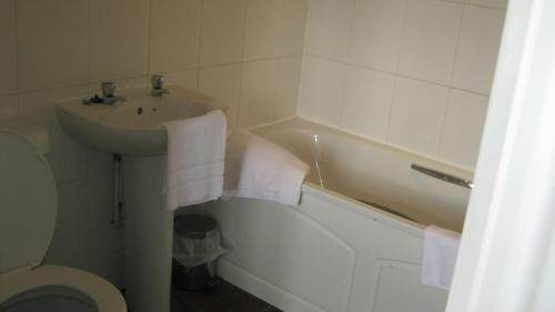 Boldre特夫卡特斯阿姆斯宾馆的一间带水槽、浴缸和卫生间的浴室