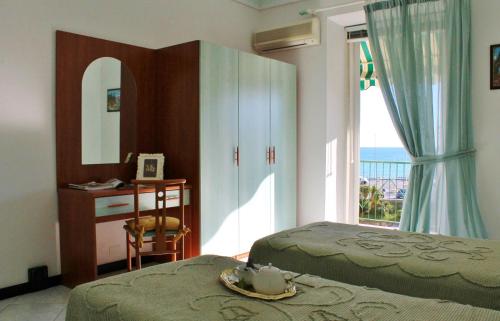上阿尔比索拉Appartamenti Mare Azzurro by Holiday World的一间卧室设有两张床、一张桌子和一个窗口。