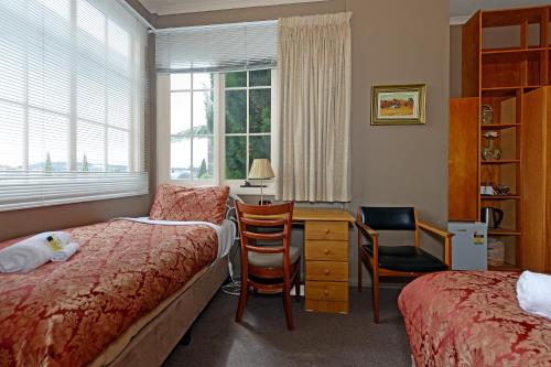 霍巴特爱丁堡画廊旅馆的一间卧室配有一张床、一张书桌和一个窗户。