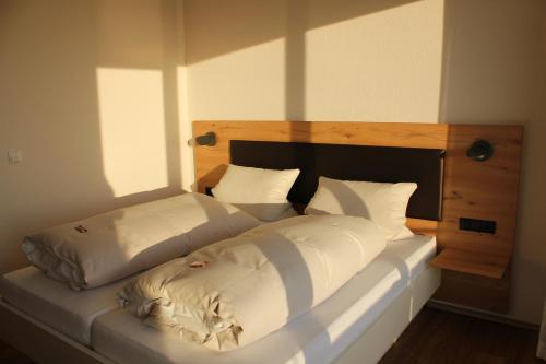 葡萄酒之路上的诺伊施塔特Gästehaus Rebenhof的一张带白色床单和枕头的床