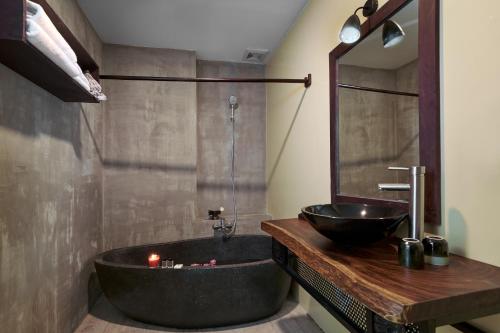 金边Monsoon Bassac Hotel的浴室配有黑色浴缸和水槽
