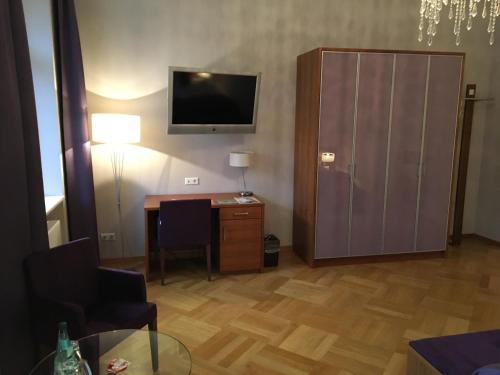 开姆尼茨拉本斯泰因城堡酒店的一间带书桌和电视的客厅以及一间房间。