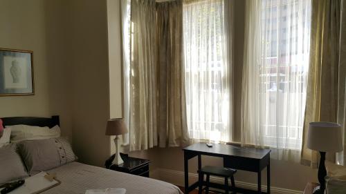 德班Sommersby Bed & Breakfast的卧室配有一张床和一张书桌,毗邻窗户