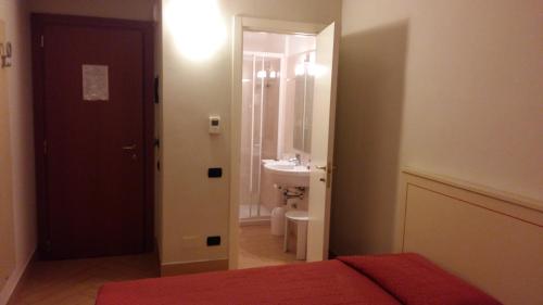 阿斯蒂Hotel Cavour的一间卧室配有一张床,浴室设有水槽