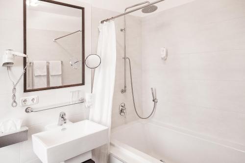 德累斯顿德累斯顿维夫酒店的白色的浴室设有水槽和浴缸。
