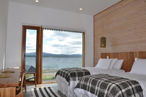 纳塔列斯港Hotel Simple Patagonia的一间卧室设有两张床和大窗户