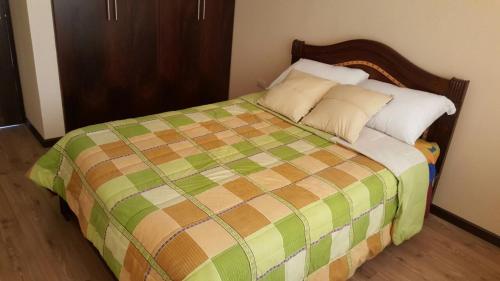 昆卡Casa Vacacional的一间卧室配有一张带绿色和棕色毯子的床