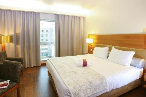 里斯本里斯本美居酒店的一间设有大床和窗户的酒店客房