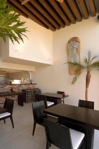 宫古岛RENN私人度假酒店的一间设有桌椅的餐厅,墙上有一棵棕榈树
