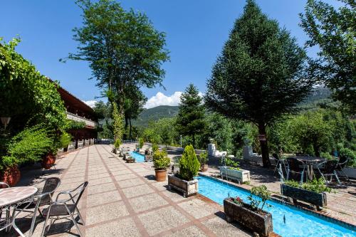 阿罗约弗里奥Hotel Rural Noguera de la Sierpe的一座带游泳池、桌子和树木的度假酒店