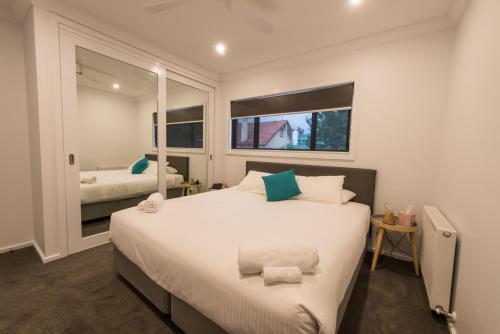 本迪戈明亮公寓的卧室设有一张白色大床和两个窗户。