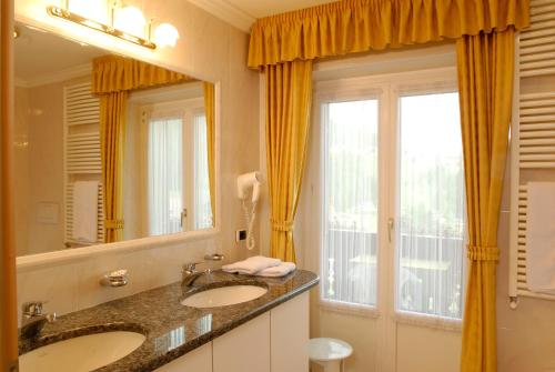 塞尔瓦迪加尔代纳山谷Garni Waltoy的一间带两个盥洗盆和大镜子的浴室