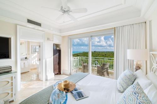 格雷斯湾特克斯和凯科斯群岛海岸俱乐部度假村的一间带白色床的客厅和一个阳台