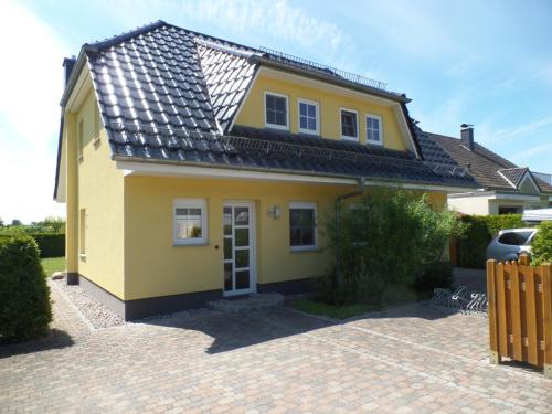 卡尔斯哈根Ferienhaus am Eikboom - DHH2 mit Fasssauna的砖车道上一座黄色房子,屋顶黑色