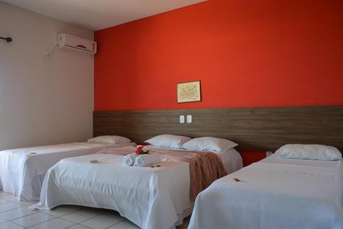 普拉杜Pousada Tropical的一间设有两张床和橙色墙壁的客房