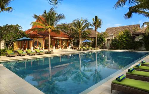 沙努尔Sudamala Resort, Sanur, Bali的一个带椅子和棕榈树的度假村游泳池