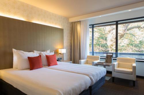 德比尔特Van der Valk Hotel de Bilt-Utrecht的一间酒店客房,设有一张大床和一个大窗户
