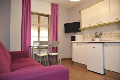 格拉纳达格拉纳达三一公寓式酒店的一间带红色沙发的客厅和一间厨房