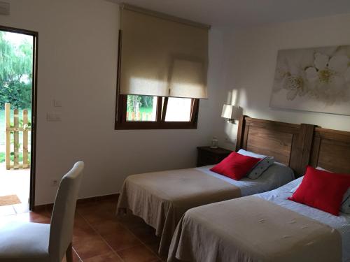 塔里法Alojamiento Mesón el Pozuelo的酒店客房 - 带两张带红色枕头的床