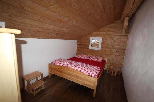 雷金根Chalet Daheim的一间位于木制房间内的小卧室,配有红色的床