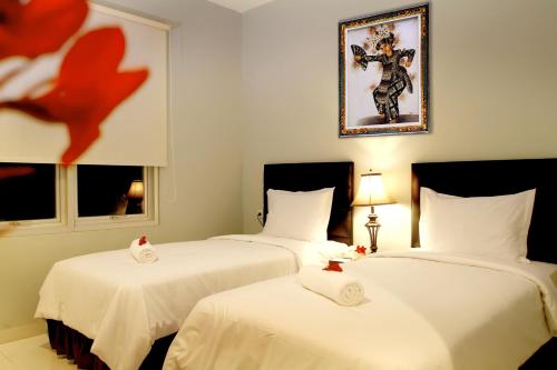 普拉亚嘉逸皇冠BIL酒店的配有白色床单的客房内的两张床