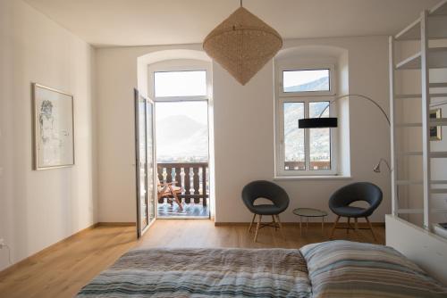 梅拉诺Fürstenstein的一间带两把椅子和一张床的卧室以及一个阳台