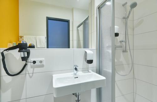 伍珀塔尔沃彼塔尔麦克乔姆斯酒店的白色的浴室设有水槽和淋浴。