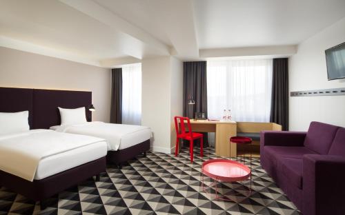 摩尔曼斯克AZIMUT City Hotel Murmansk的酒店客房带两张床、一张沙发和一张桌子