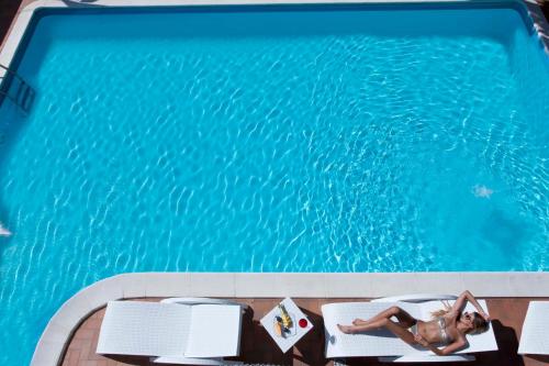 里米尼日光酒店的躺在游泳池旁床边的女人
