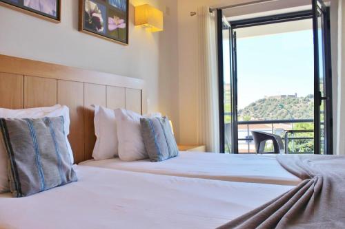 阿尔热祖尔Vicentina Hotel的一间卧室设有两张床和大窗户
