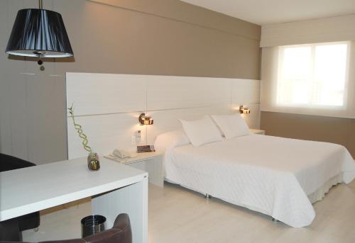 佩洛塔斯塔酒店的卧室配有白色的床、书桌和床。