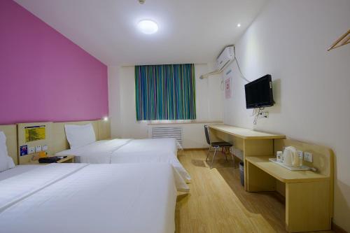 上海7天上海闵行东川路交大店的酒店客房配有两张床和一张书桌