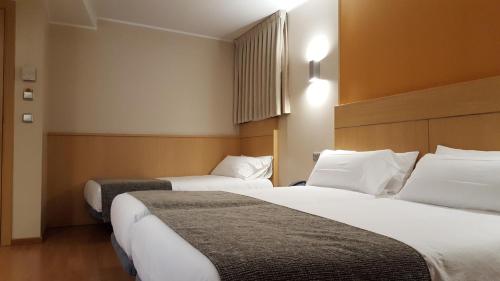 安道尔城埃斯佩尔酒店的配有白色枕头的酒店客房内的两张床