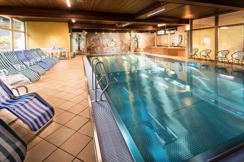 费尔兹姆斯汉内斯霍夫活力及保健酒店的大型游泳池配有躺椅和四柱床