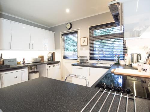 MaidfordYew Tree Cottage的厨房配有白色橱柜和黑色台面