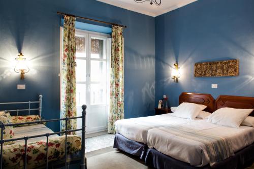 塞维利亚阿巴尼科酒店的一间蓝色卧室,配有两张床和窗户