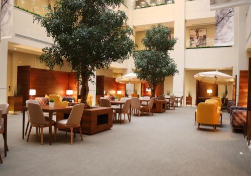 利雅德Rafa - Al Nuzhah的酒店大堂设有桌椅和树木