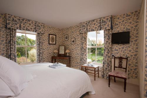 纽伯里Rookwood Farmhouse B&B的卧室配有一张床,墙上配有电视。