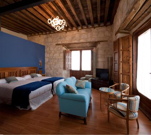 Valoria la Buena会议旅馆的一间卧室配有一张大床和一张蓝色的沙发