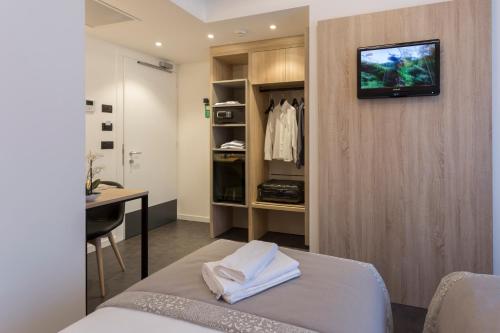 布列瑟农旅游者酒店的一间设有床铺和书桌的房间,墙上设有一台电视机