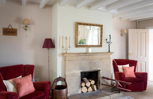 布罗德韦Lowerfield Farm的客厅配有2把红色椅子和壁炉