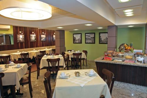 约恩维利普林西比酒店 的一间设有白色桌椅的餐厅,拥有绿色的墙壁