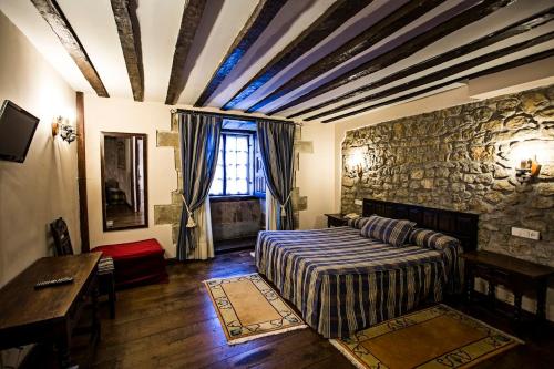 桑提亚纳德玛阿尔塔米拉酒店的一间卧室设有一张床和石墙